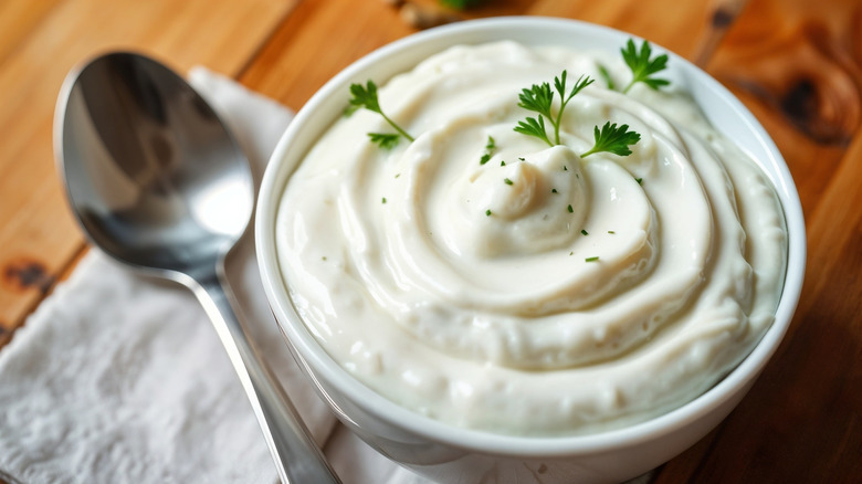 Garlic and herb dipping sauce in a bowl with a spoon on the side