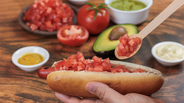 Person adding toppings to a completo