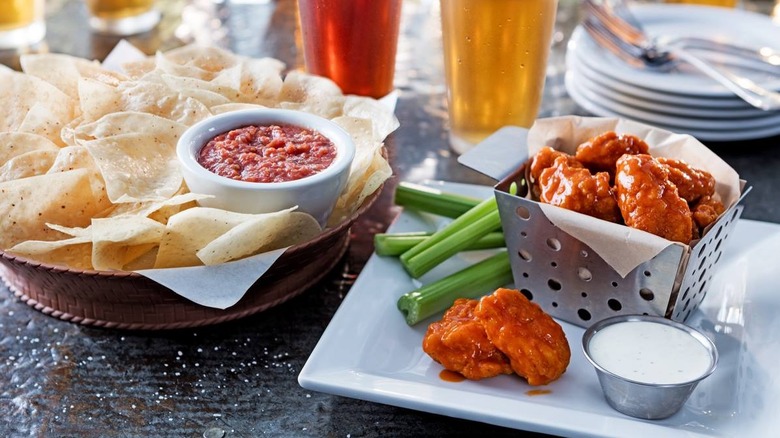 Basket of Chili's wings with ranch and a basket of chips and salsa on a table