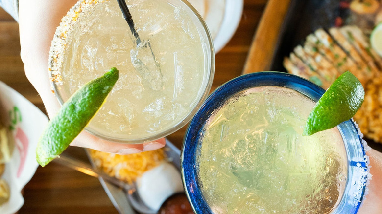 Overhead view of hands bringing Chili's margaritas together over an assortment of food