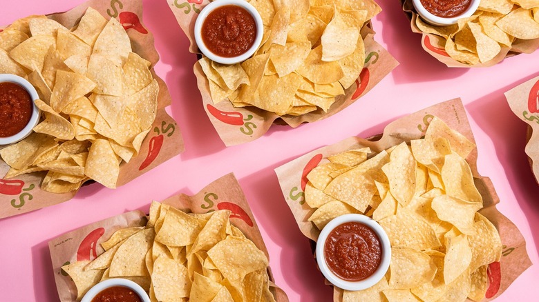 Overhead view of baskets of Chili's chips and salsa on a pink tabletop