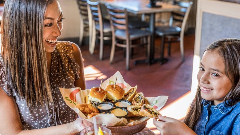 Happy woman and child enjoying basket of assorted Chili's appetizers