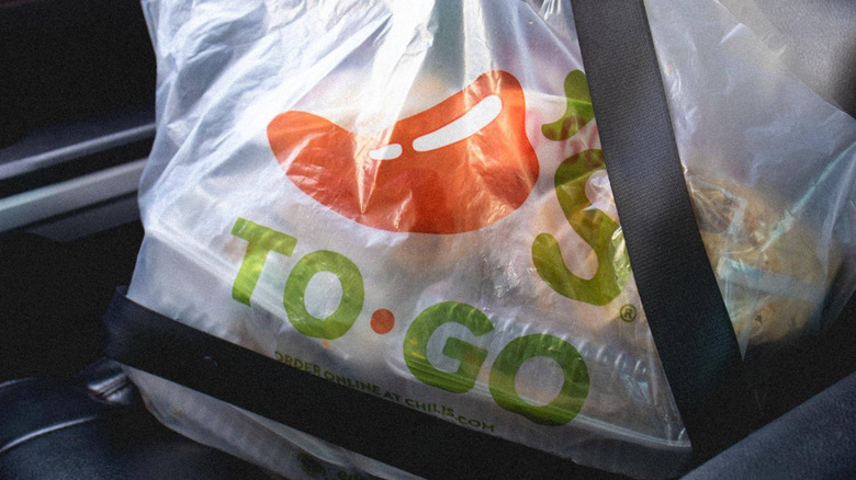 Bag of to-go food from Chili's buckled into the seat of a car