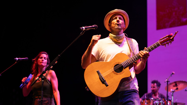 Jason Mraz performing on stage with an acoustic guitar