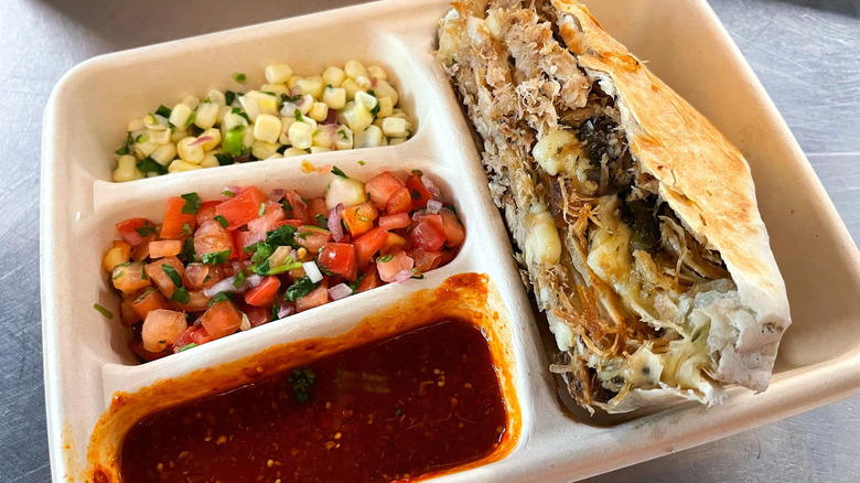 The salsa and hot sauce from Chipotle in a takeout box with a quesadilla