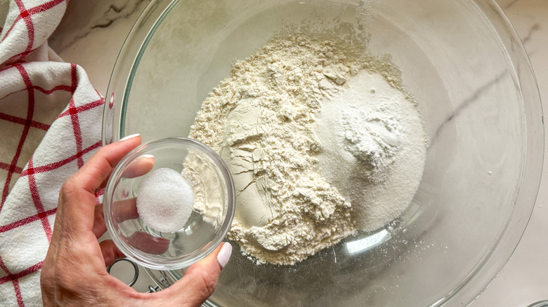 hand adding salt to bowl