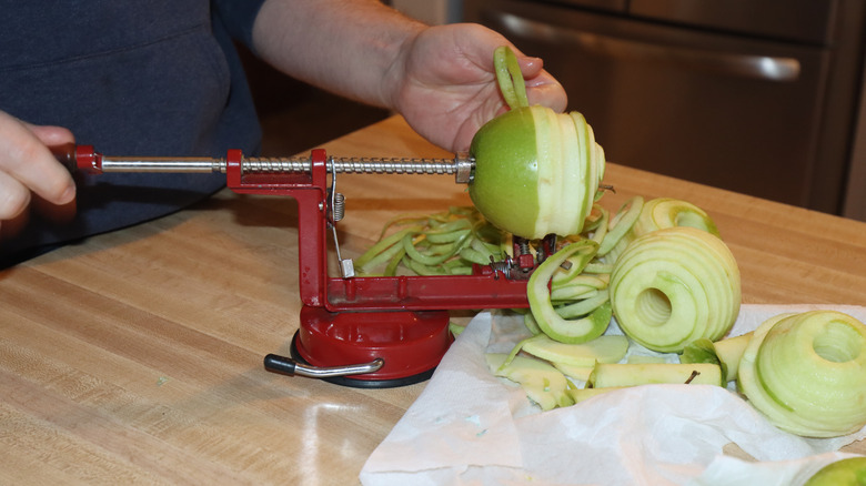 person using a cast iron apple peeler