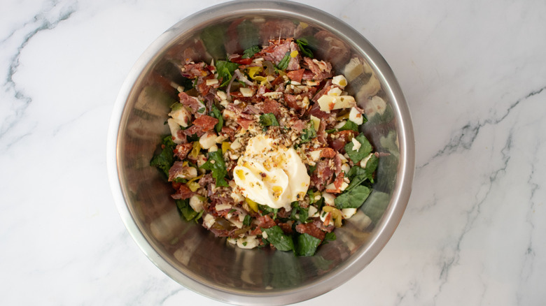 Chopped Italian sandwich ingredients in a large bowl with mayonnaise and Italian dressing