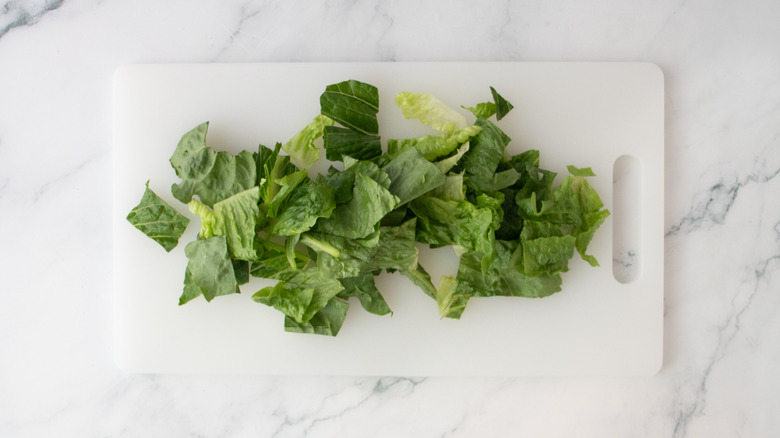 Chopped lettuce on a large white cutting board