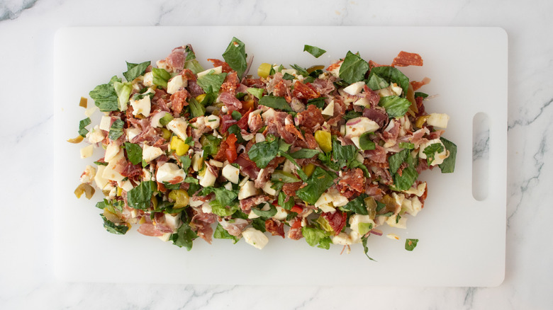 Chopped Italian sandwich ingredients on a cutting board