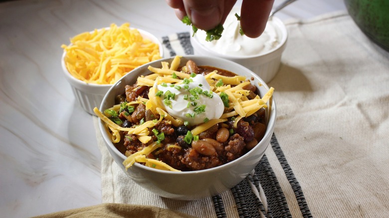 sprinkling chives onto bowl of chili