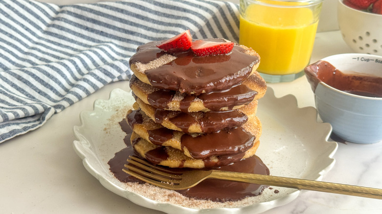 Churro pancakes with chocolate drizzle stacked on plate