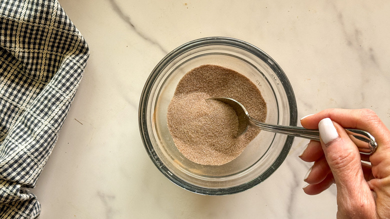hand stirring cinnamon sugar mixture in bowl