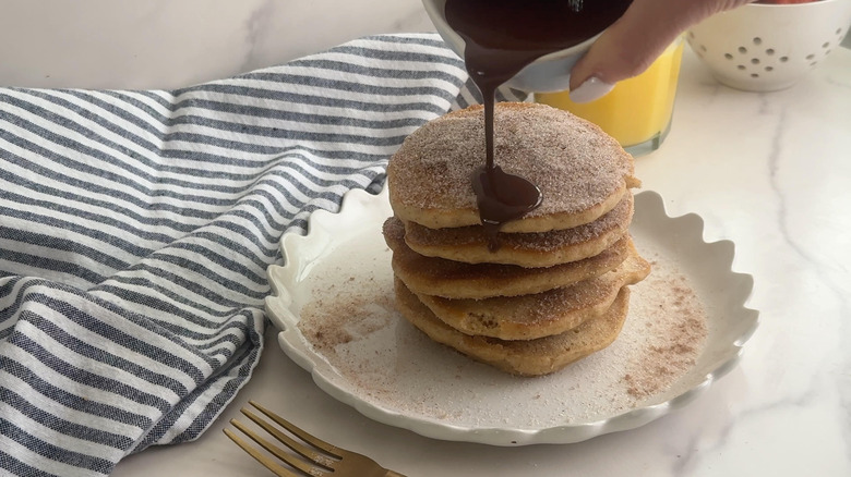 pouring chocolate onto cinnamon churro pancakes
