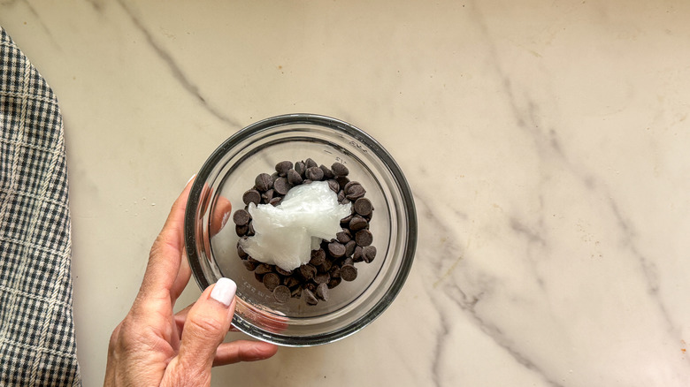 hand holding bowl of chocolate with coconut oil