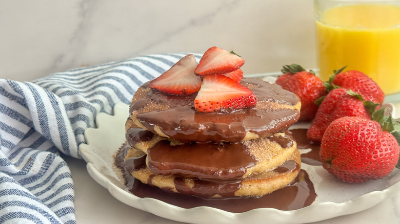 Churro pancake stack with chocolate drizzle and strawberries