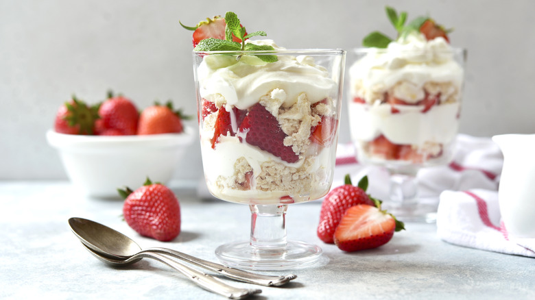 Pretty trifle bowls contain Eton mess; layers of meringue, whipped cream, and strawberries.