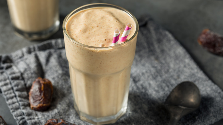 Date shake with pink-and-white striped straws in clear glass