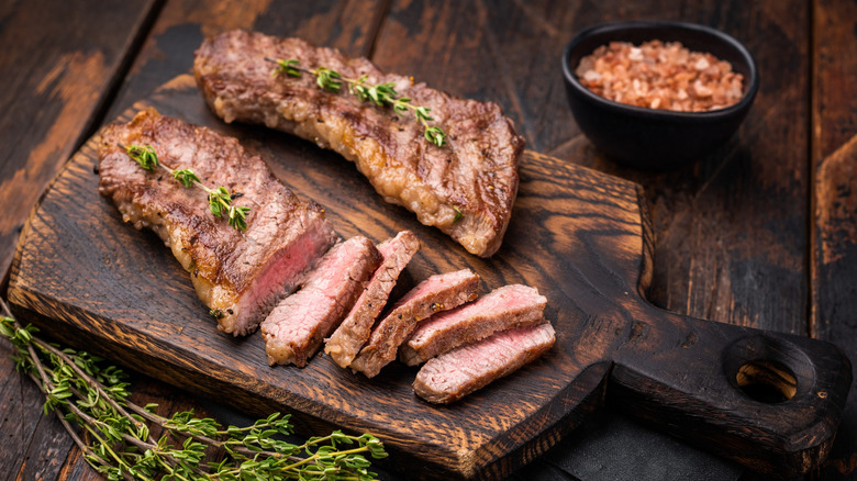 Tri-tip steaks on wooden cutting boat with rosemary sprigs alongside