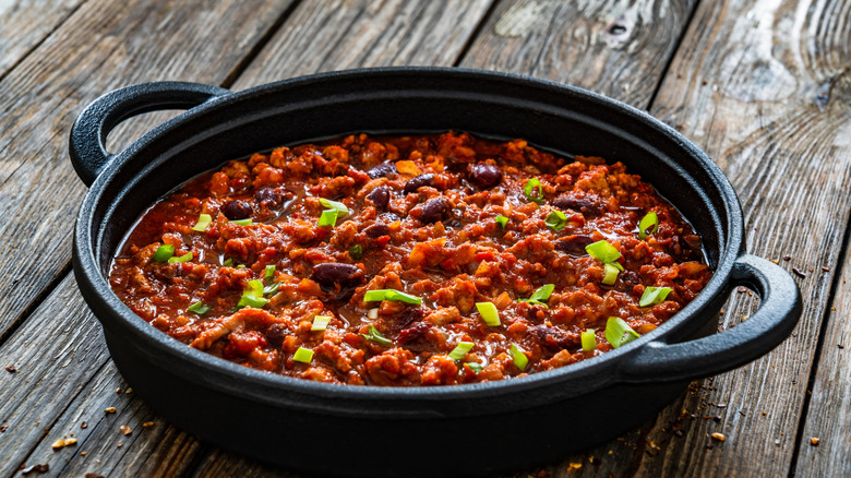 Chili con carne in cast iron pan on wooden table