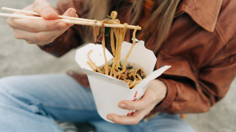woman eating from Chinese take out container