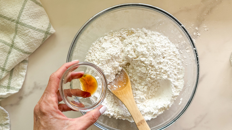Small bowl of vanilla going into larger bowl with powdered sugar