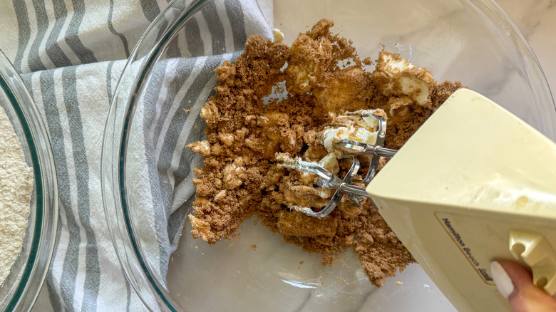 Electric mixer beating butter and brown sugar in bowl