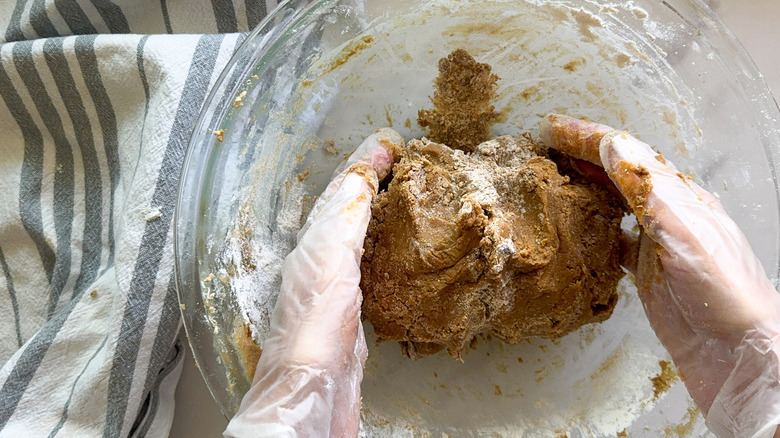Hands forming gingerbread cookie dough in bowl