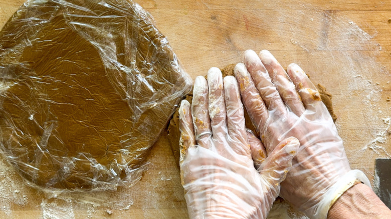 hands flattening gingerbread cookie dough