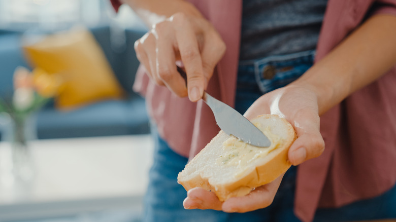Person spreading butter on a slice of bread