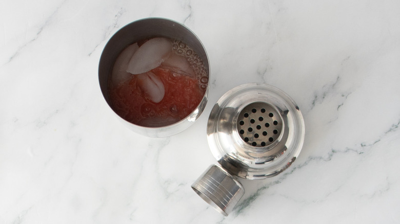 Cocktail shaker with ice and citrus juice