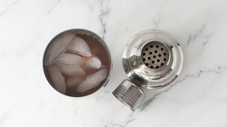 Cocktail shaker filled with ice, liquor, and citrus juice