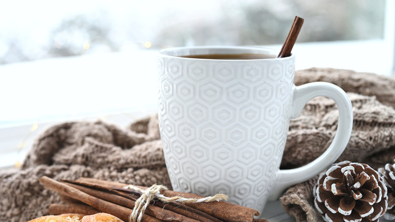Warm cup of coffee grog with a cinnamon stick to stir