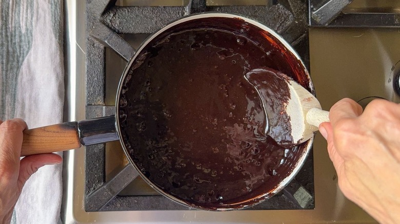 Classic hot fudge sauce coming to a boil in saucepan on stovetop