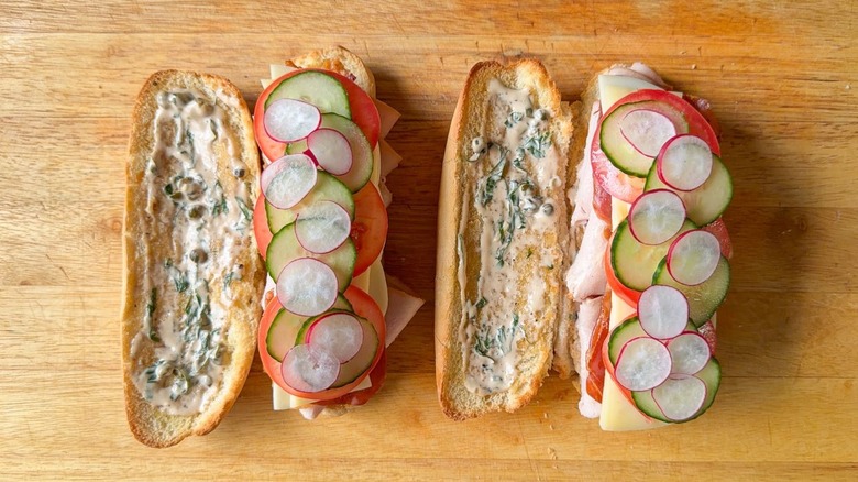 Thin slices of cucumber and radish on top of meats and cheeses in classic Italian-ish club sub sandwich