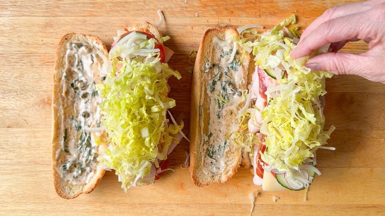 Piling shaved fennel and shredded lettuce on top of classic Italian-ish club sub sandwich