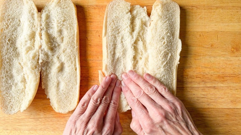 Pressing down on the insides of sliced Italian rolls