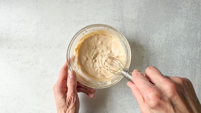 Whisking together sub sandwich dressing ingredients in small glass bowl