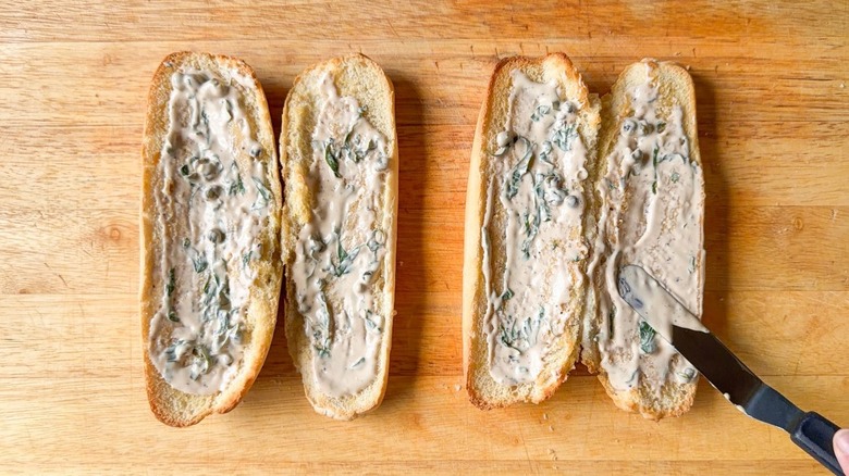 Spreading dressing on toasted Italian rolls