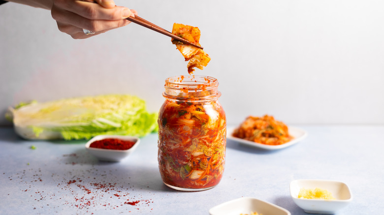 chopsticks taking some kimchi from jar 