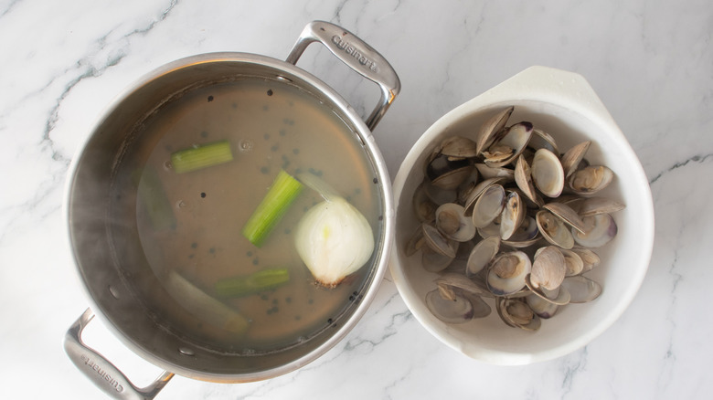 bowl of clams next to a pot of vegetables in liquid