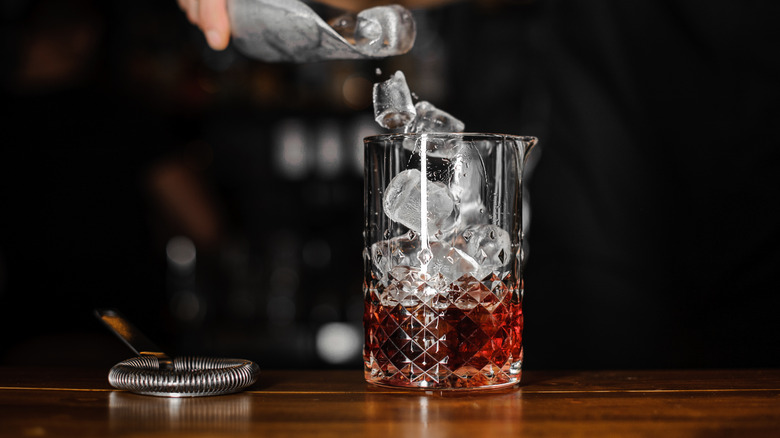 A cocktail mixing glass with ice cubes ready to stir and chill a rum old fashioned
