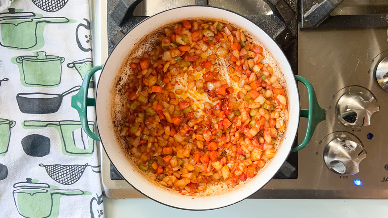 Vegetables and tomato paste in pot on stove
