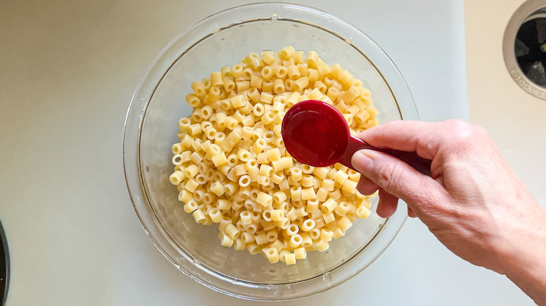 Adding olive oil to ditalini pasta in bowl