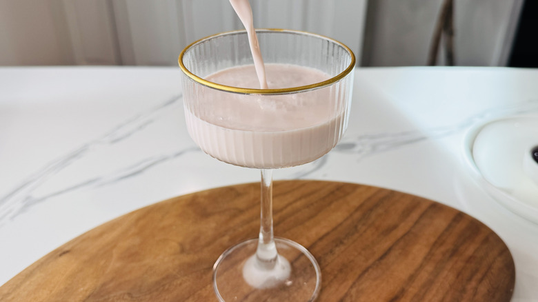 Straining pink squirrel cocktail into glass