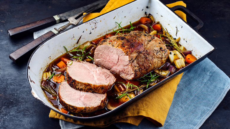 Pork roast with veggies and herbs in a baking dish