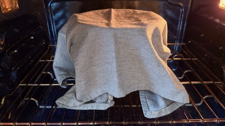 Stand mixer bowl covered with a towel in an oven