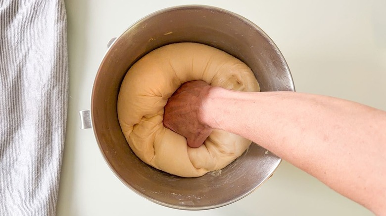 Punching down proofed beignet dough in stand mixer bowl