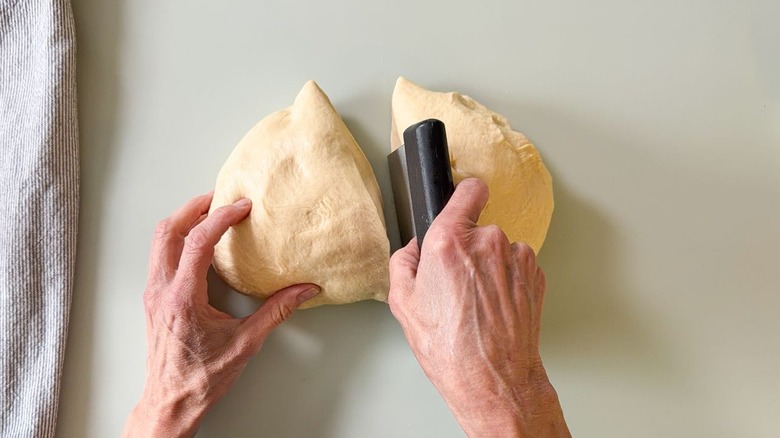 Cutting beignet dough in half with a dough cutter