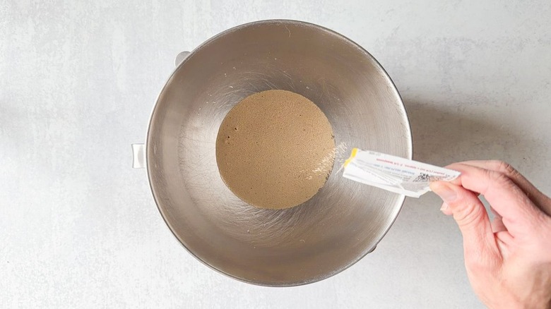 Sprinkling yeast into stand mixer bowl with warm water